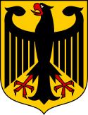 Coat of arms featuring a large black eagle with wings spread and beak open. The eagle is black, with red talons and beak, and is over a gold background.